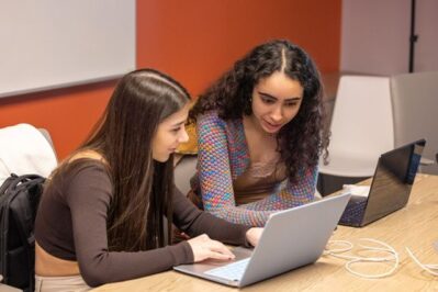 Two students collaborating on the Finiverse app, working on laptops