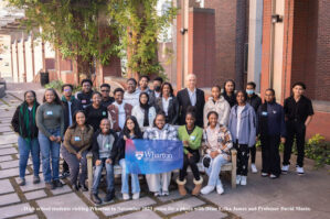 High school students visiting Wharton in November 2023 pause for a photo with Dean Erika James and Professor David Musto