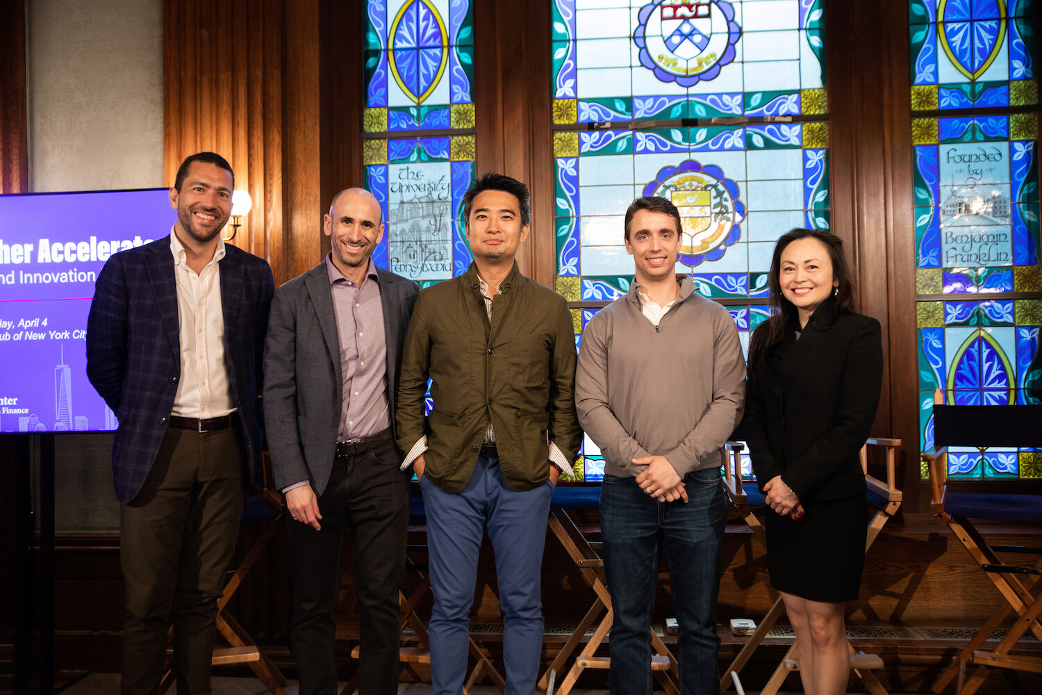 Five Demo Day panelists pose for a group photo, smiling toward the viewer