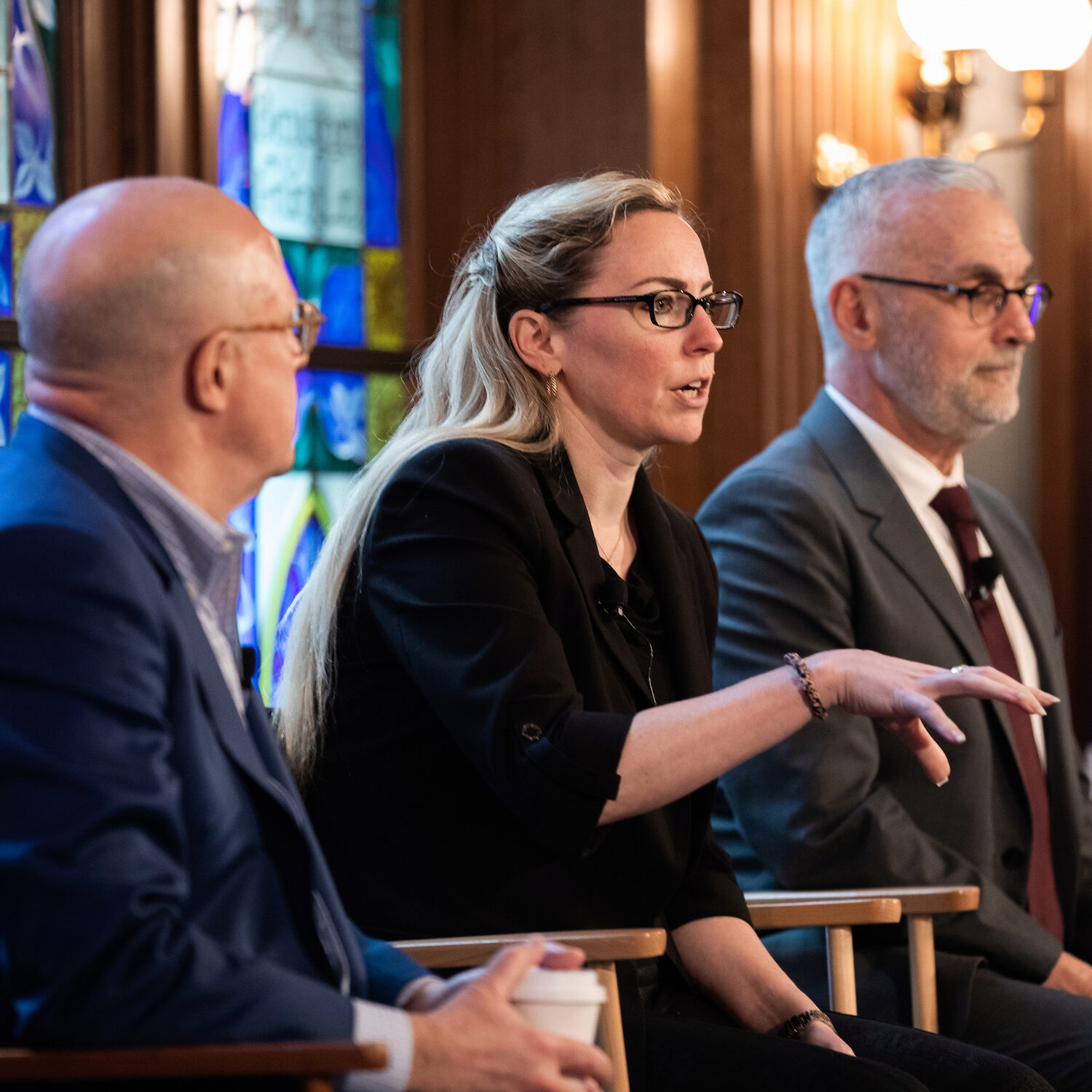 A panelist speaks while seated, as two other panelists react