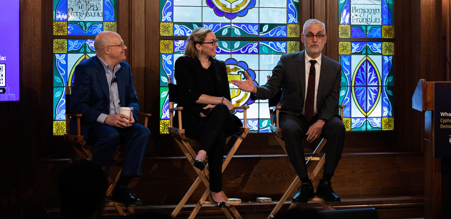 Three panelists seated in front of a stained glass window
