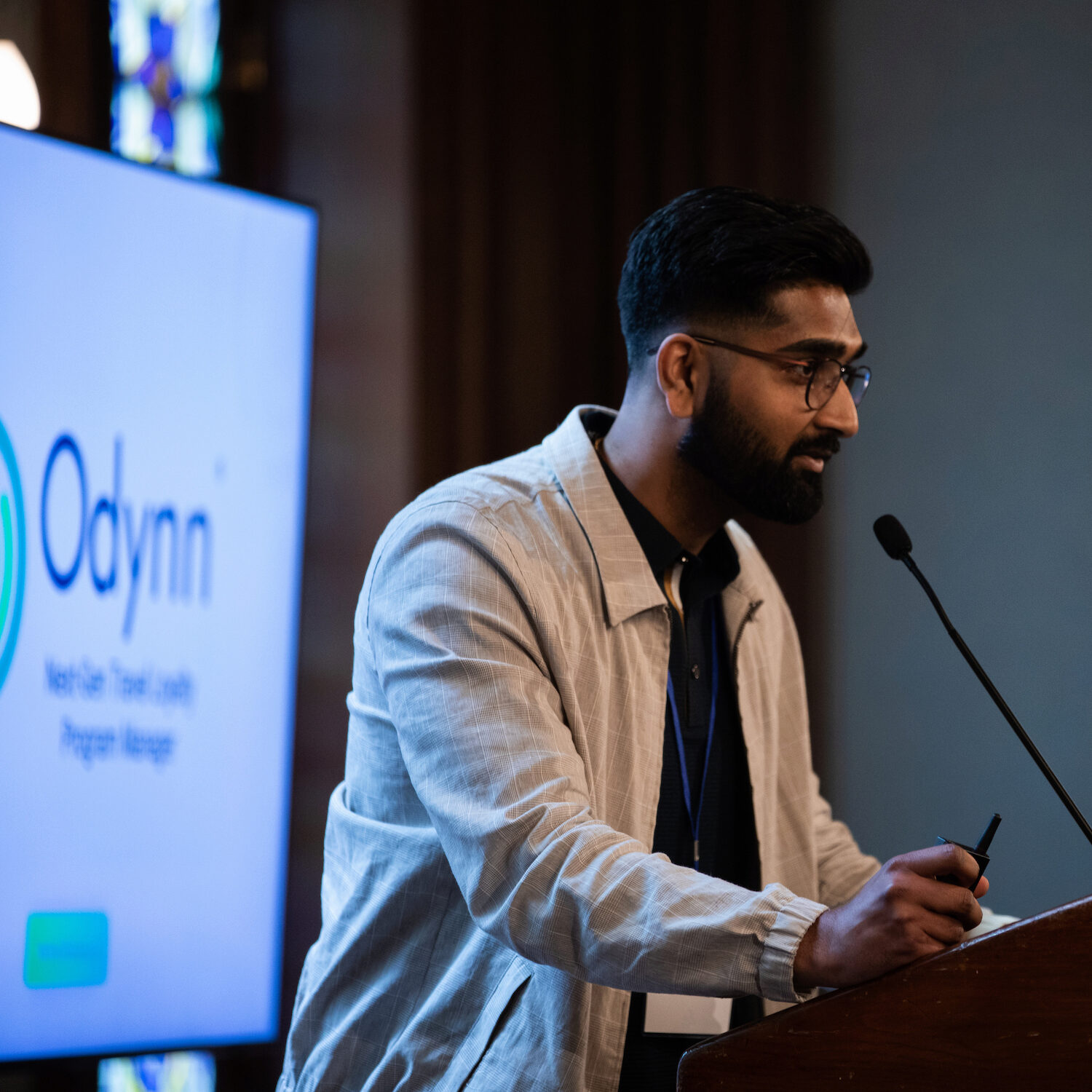 A speaker at a podium in front of a blue screen that says "Odynn"