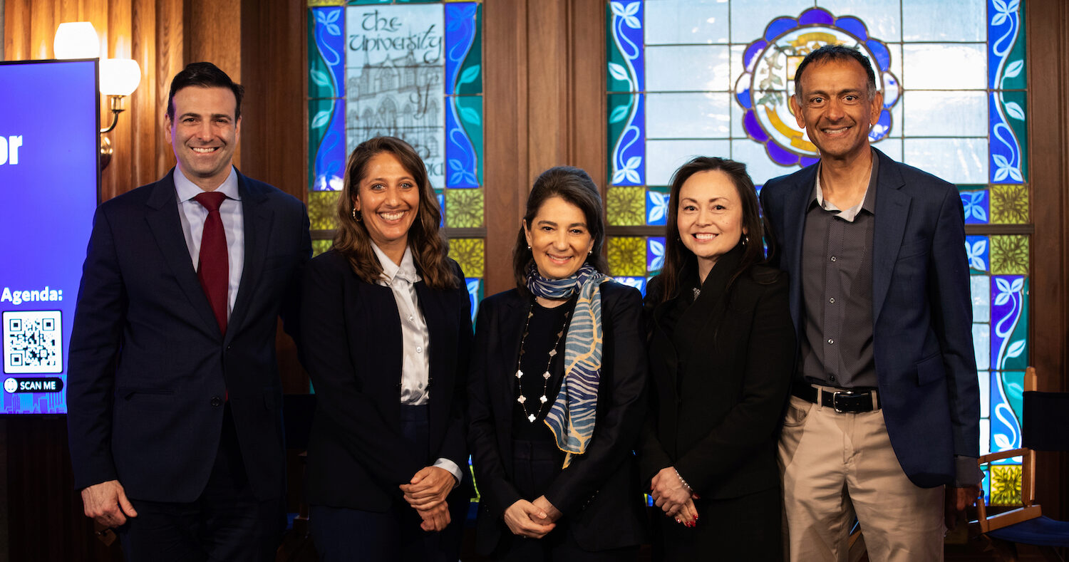 Five people pose for a group photo, smiling toward the viewer