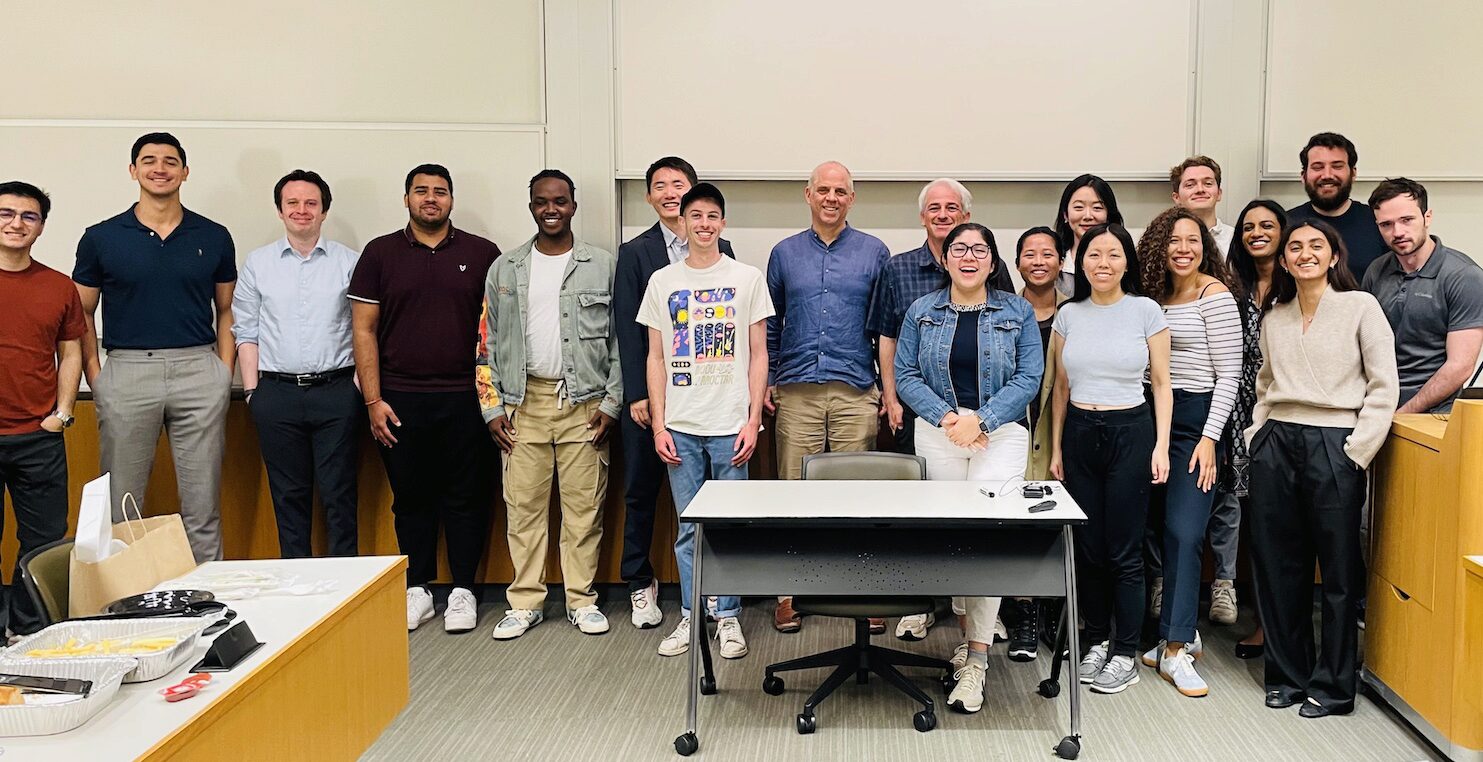 A group of people pose for a photo in a classroom setting.