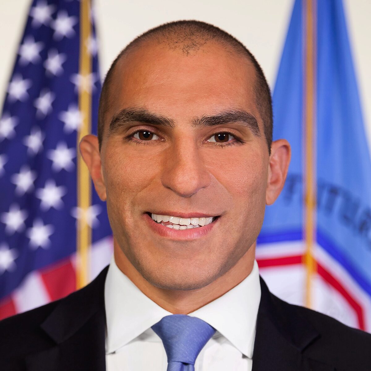 A person smiles with flags behind him